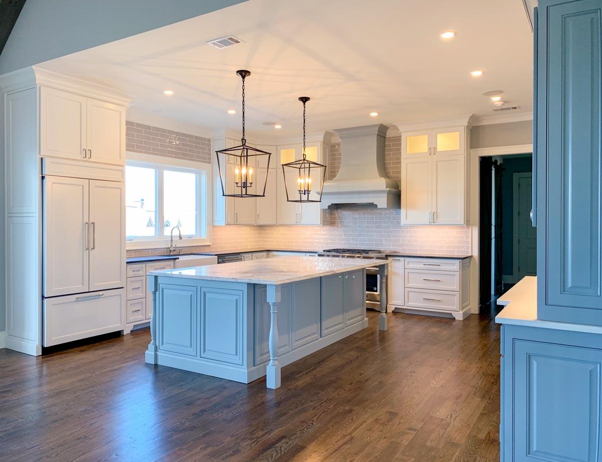 Kitchen with large center island, white cabinets, gray subway tile backsplash, and pendant lighting.
