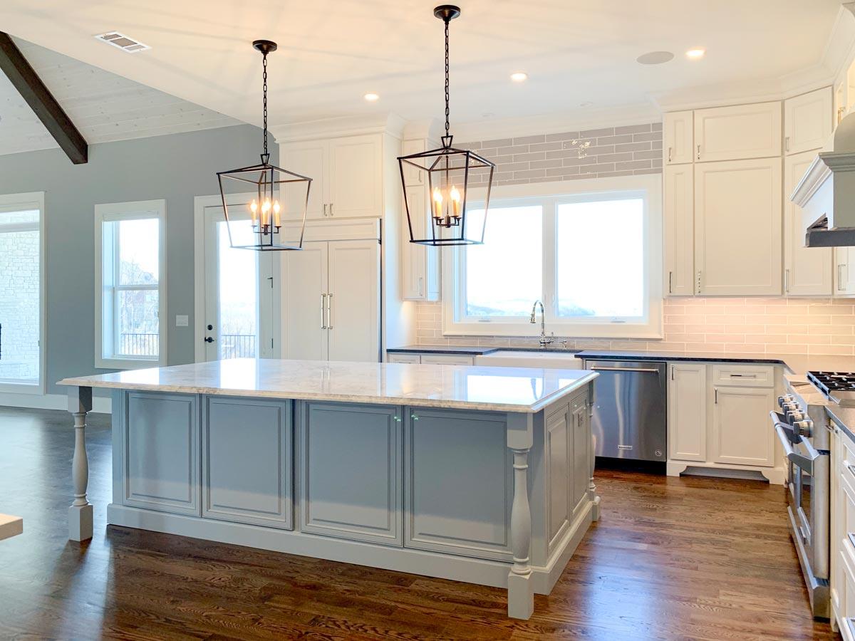 Kitchen with large island, white cabinets, stainless steel appliances, and vaulted ceiling with exposed beam.