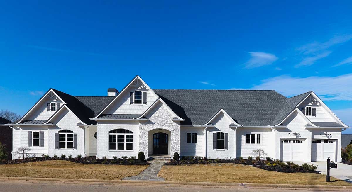Modern Farmhouse style house plan exterior with a white brick and siding facade, prominent gables, dormers, and a three-car garage.