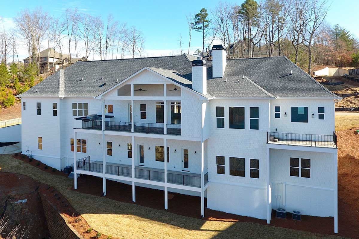 House plan exterior: White multi-story home with multiple balconies, gables, and chimneys.