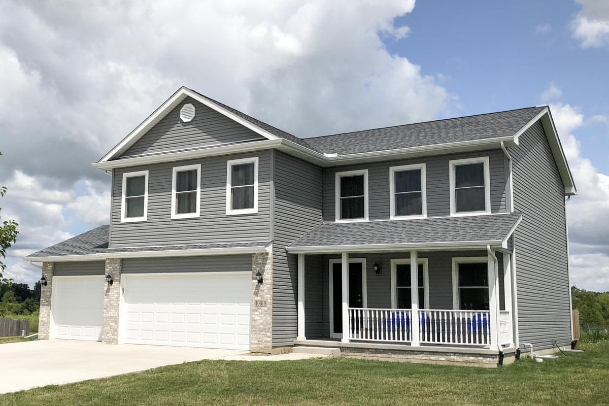 Two-story house plan exterior with gray siding, white trim, a covered front porch, and a three-car garage.