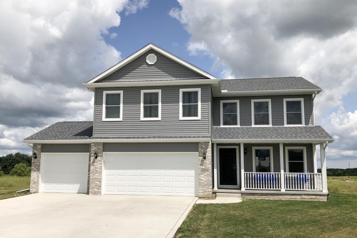 Two-story house plan exterior with gray siding, a covered front porch with white railings, and a three-car garage.