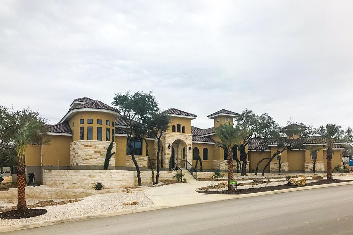 House plan exterior featuring a two-story Mediterranean-style residence with arched entryway, stucco finish, stone accents, and tiled roofs.