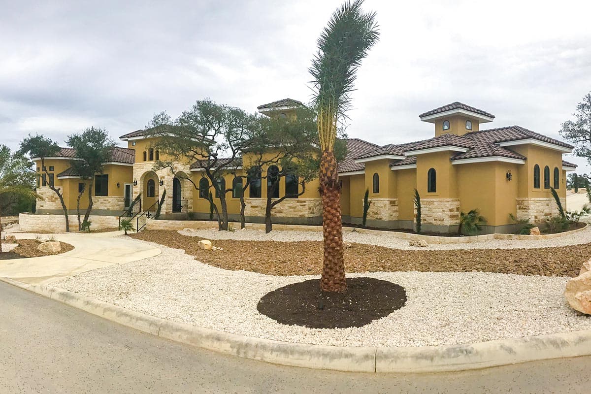 House plan exterior: Mediterranean style, stucco finish, tile roof, arched windows, stone accents, and multiple turrets.