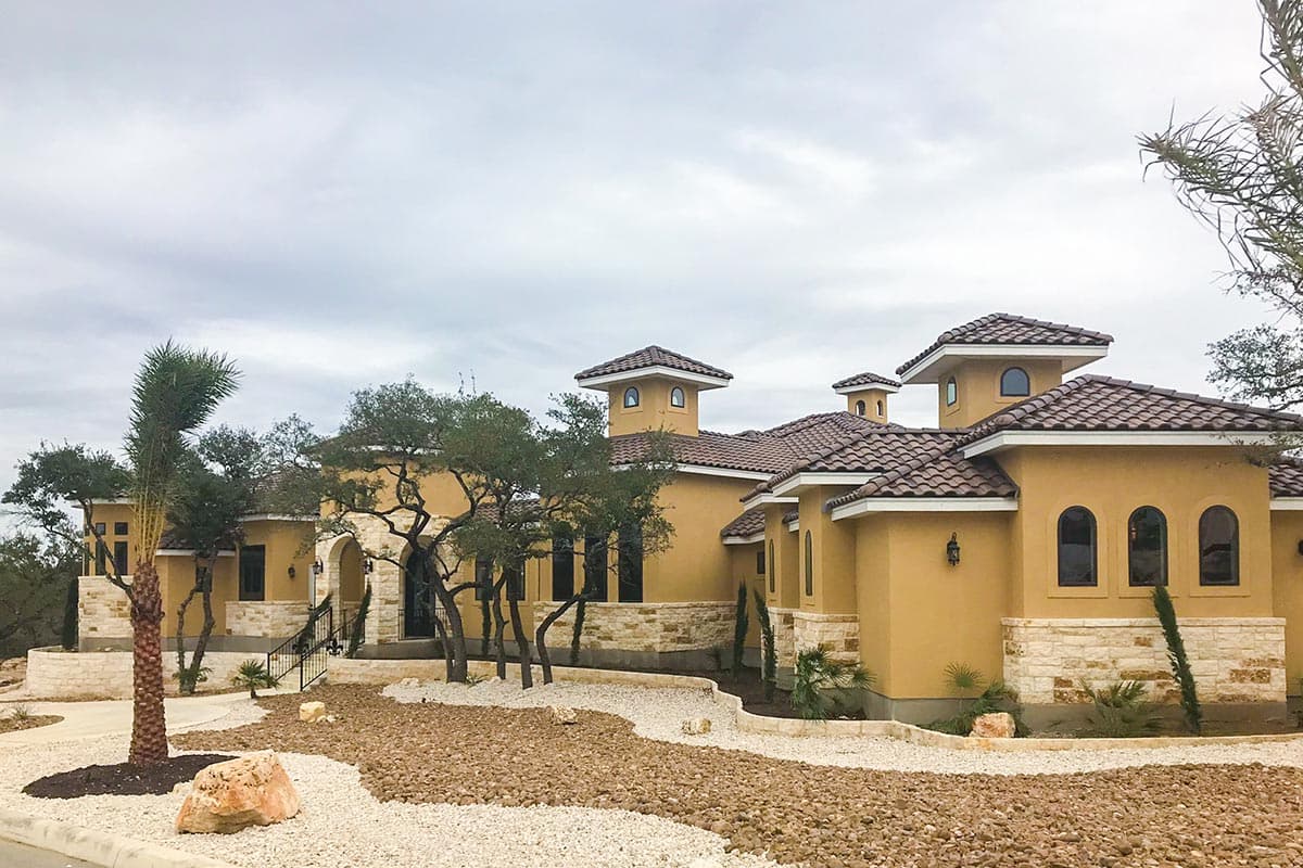 House plan exterior: Mediterranean style, stucco facade, tile roofs, arched windows, and turrets.