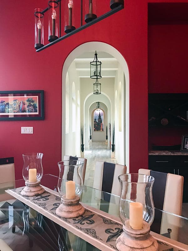 Interior view of a hallway with multiple arched doorways and hanging lanterns. Dining table in foreground.