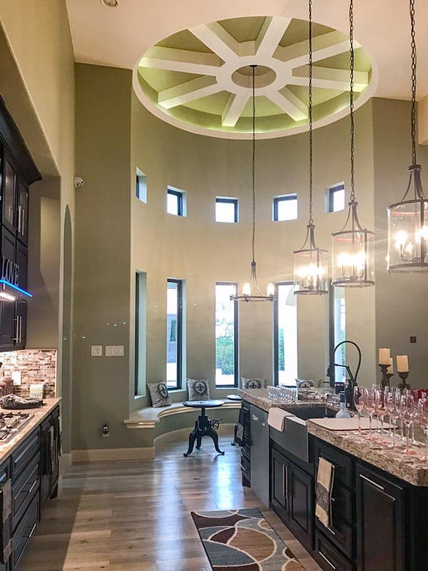 Interior view of a spacious kitchen with a large island and a tiered circular ceiling design with recessed lighting.
