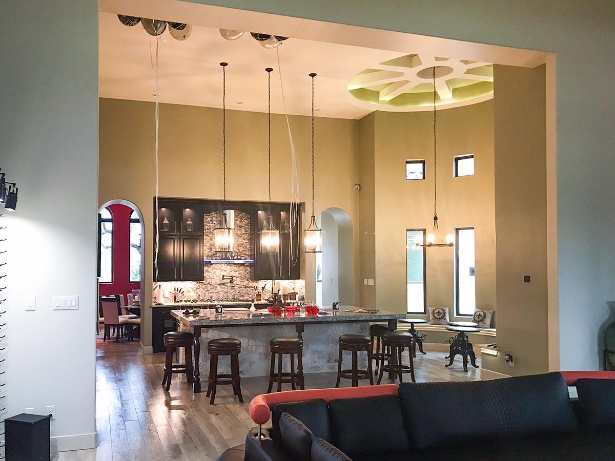 Open concept living space with island kitchen, dining area, and vaulted ceiling with decorative light fixture.