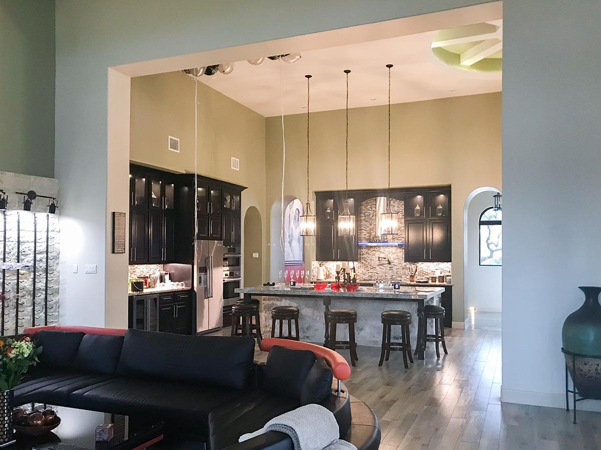 Open-concept living area with a large kitchen island, dark cabinetry, vaulted ceilings, and arched doorways.