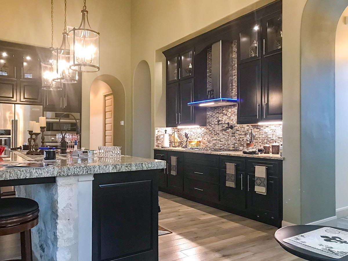 Kitchen interior with black cabinets, granite island, stainless steel appliances, and mosaic tile backsplash.
