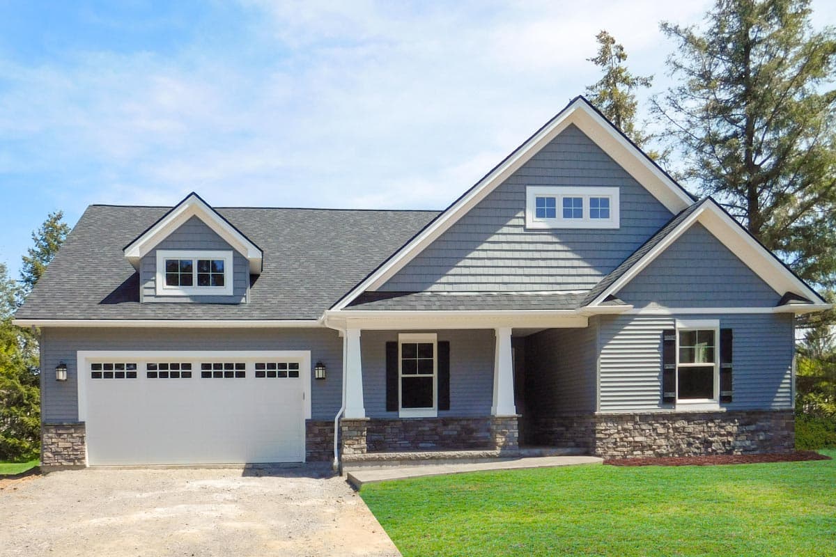 House plan exterior with two stories. Features include gabled roof, stone veneer on the base, a front porch, and dormer windows.