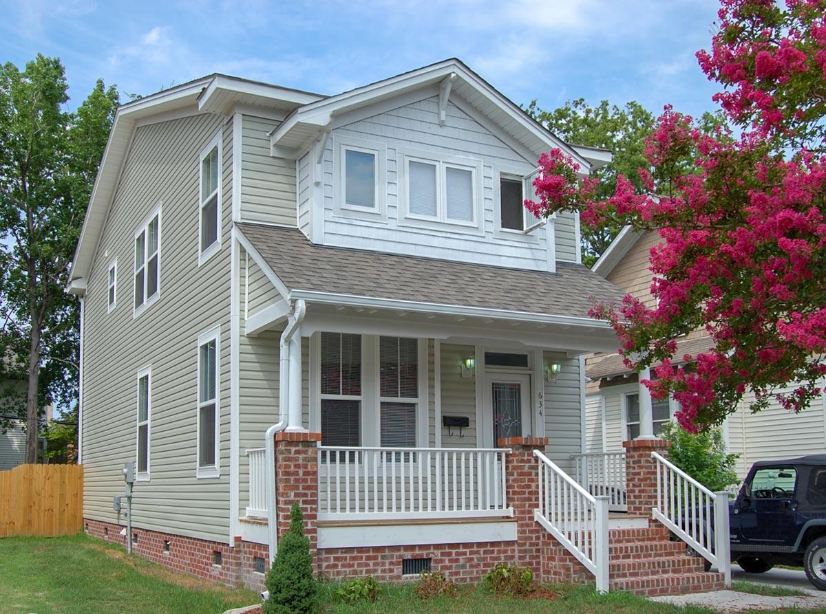 House plan exterior. Two-story house with a front porch, gables, and a prominent roofline. Features brick and siding exterior.