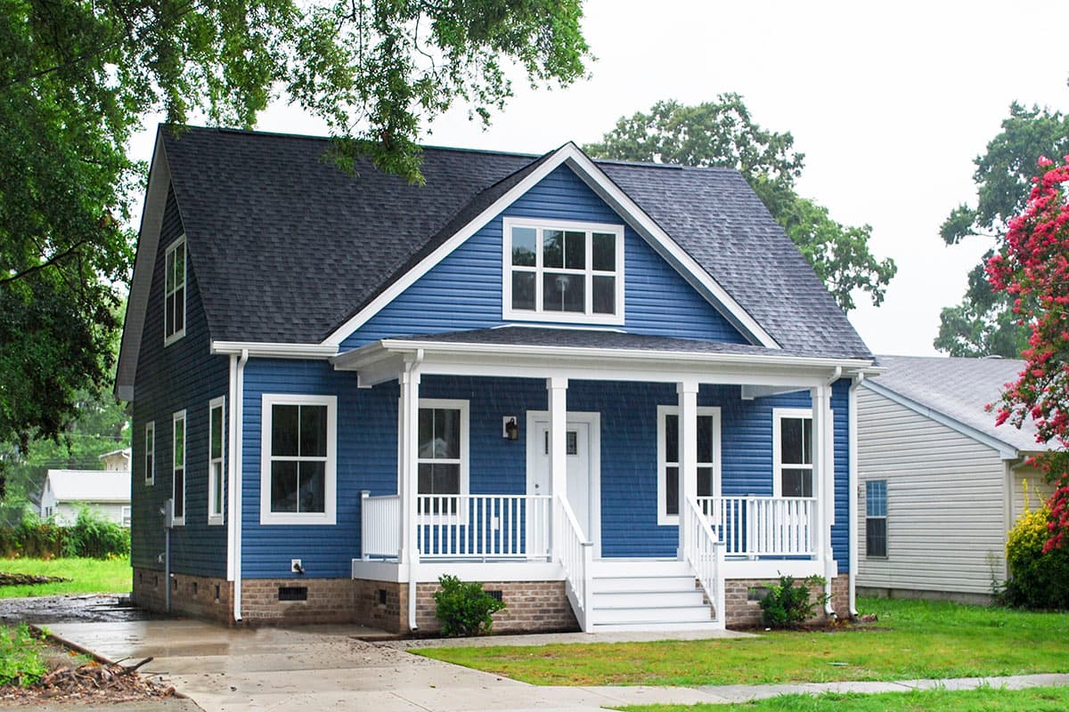 Two-story house plan exterior with a front porch, gables, and dormers.