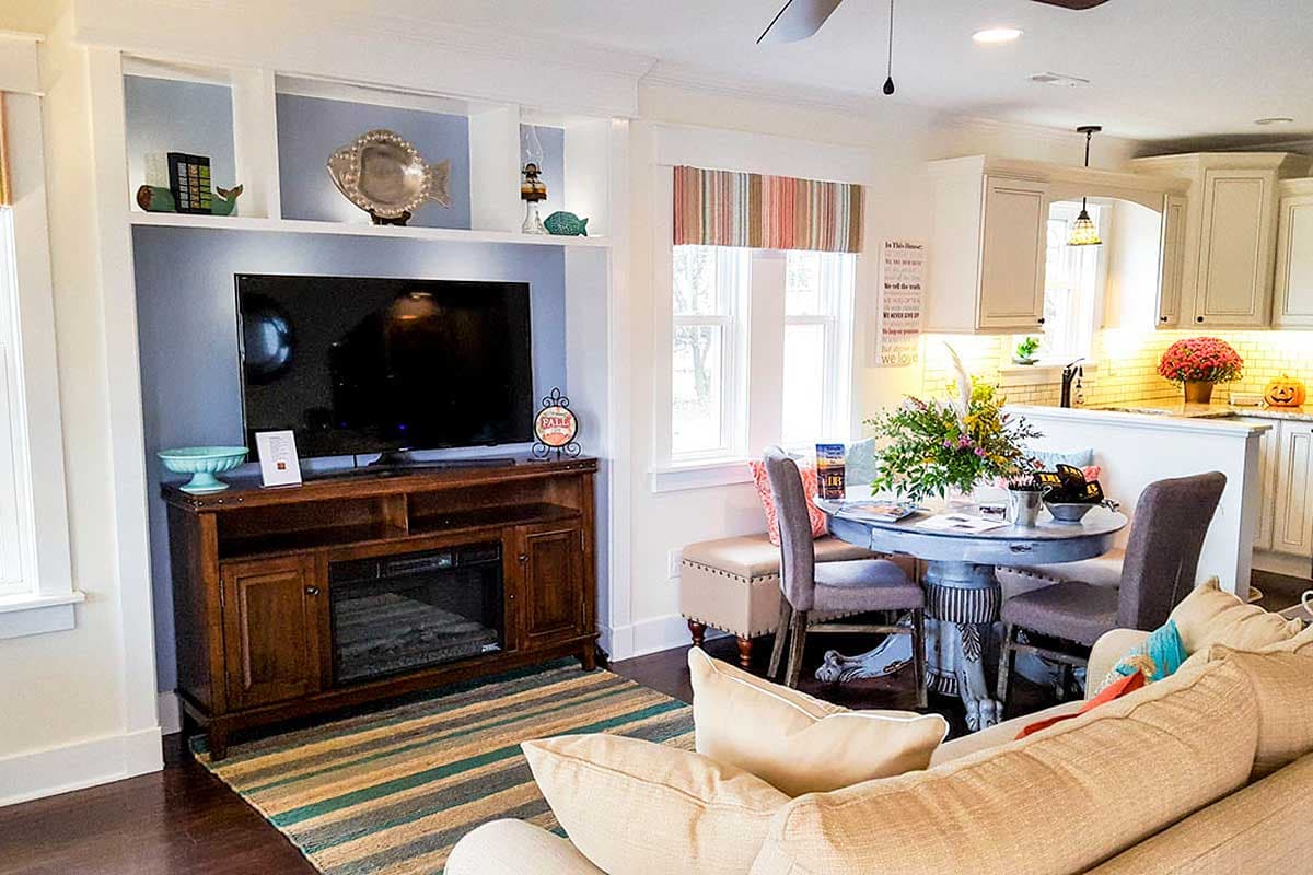 Open concept living area with built-in media console, dining nook with banquette seating, and kitchen island.