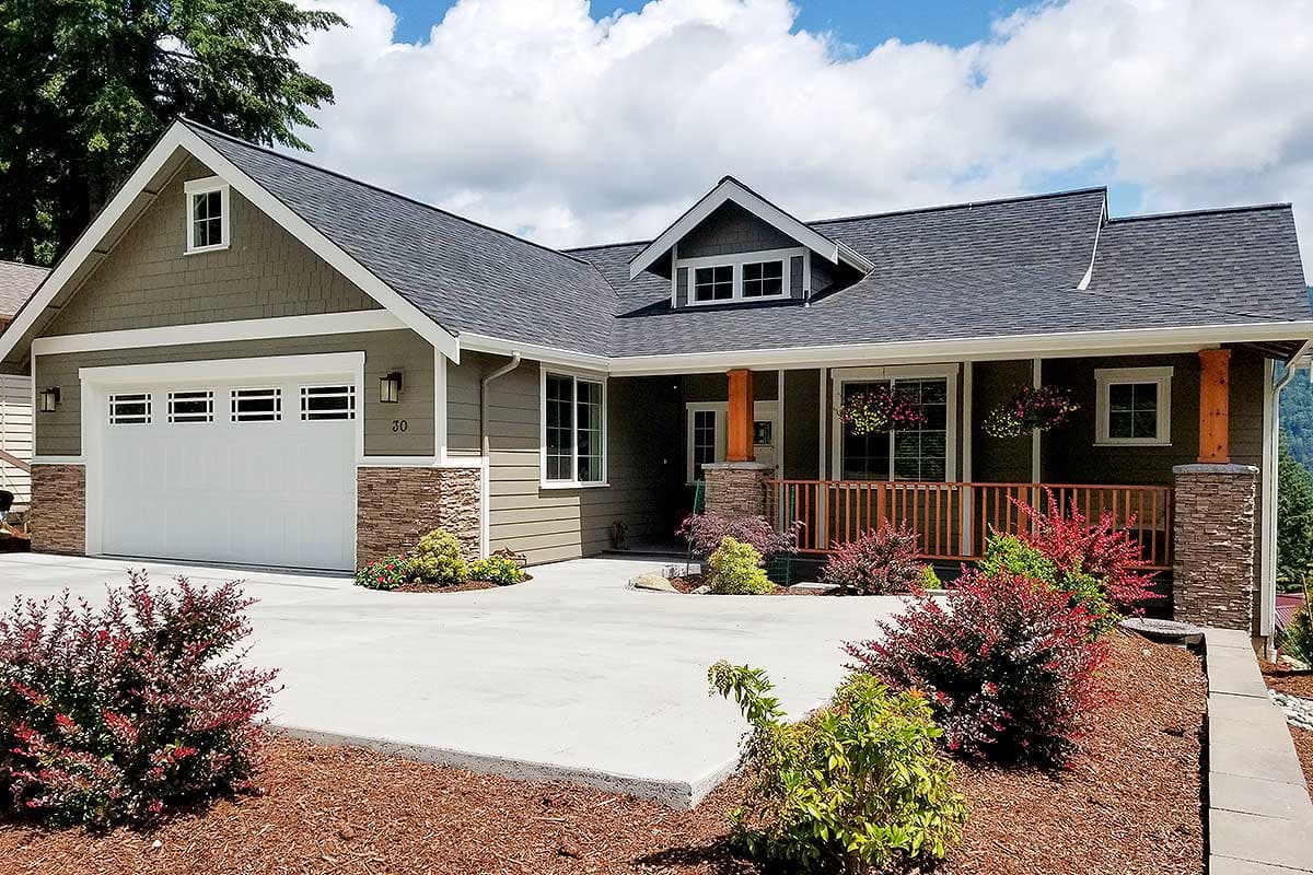 House plan exterior. Craftsman style, single-story home with a gabled roof, stone accents on the porch supports, and a covered front porch.