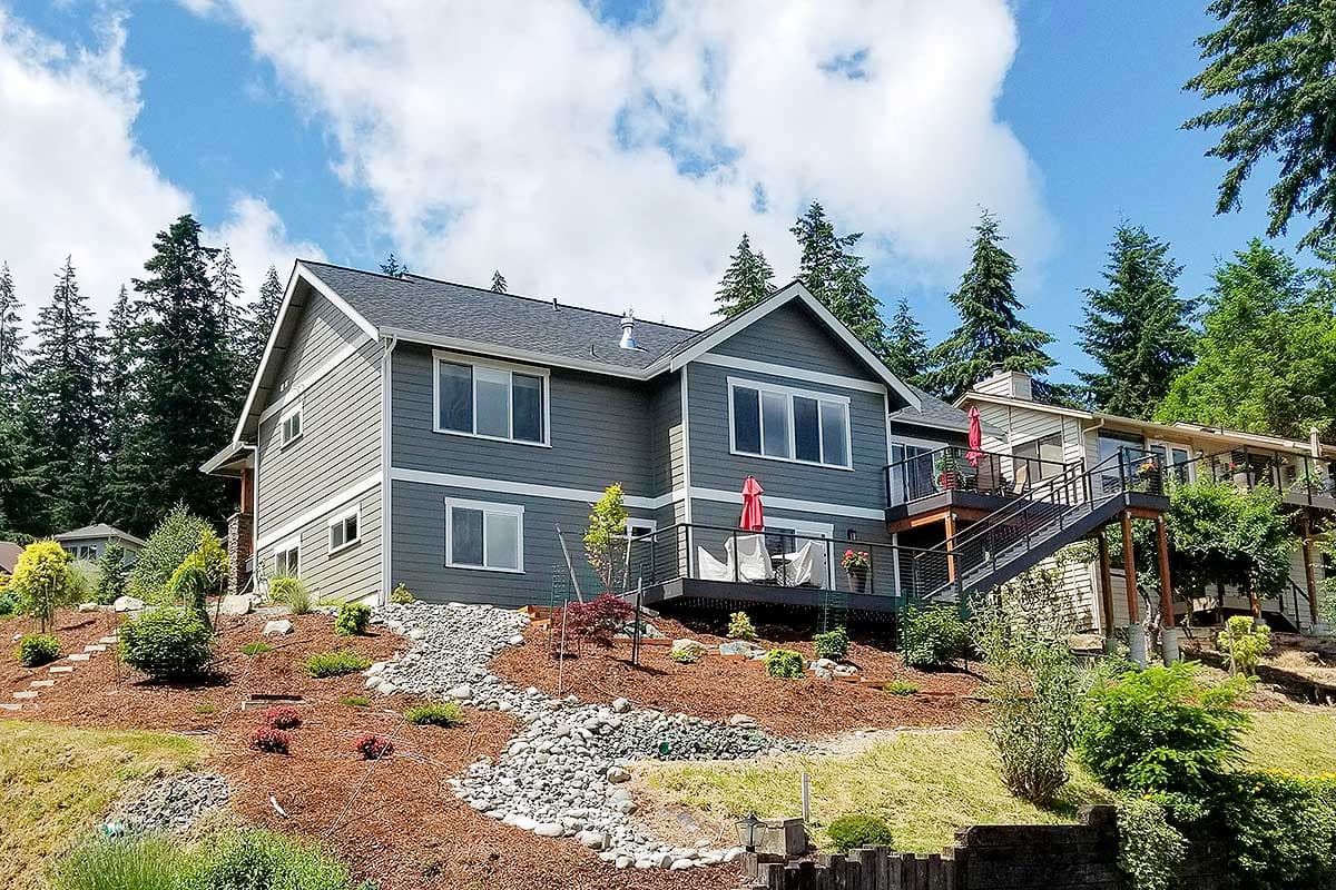 Two-story modern house plan exterior with horizontal siding, gable roof, and tiered deck with stairs.