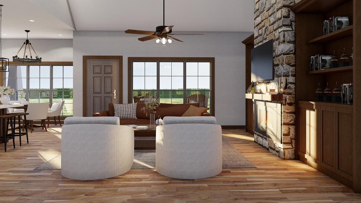 Open-concept living area with stone fireplace, built-in bookshelves, dining nook, and large windows.