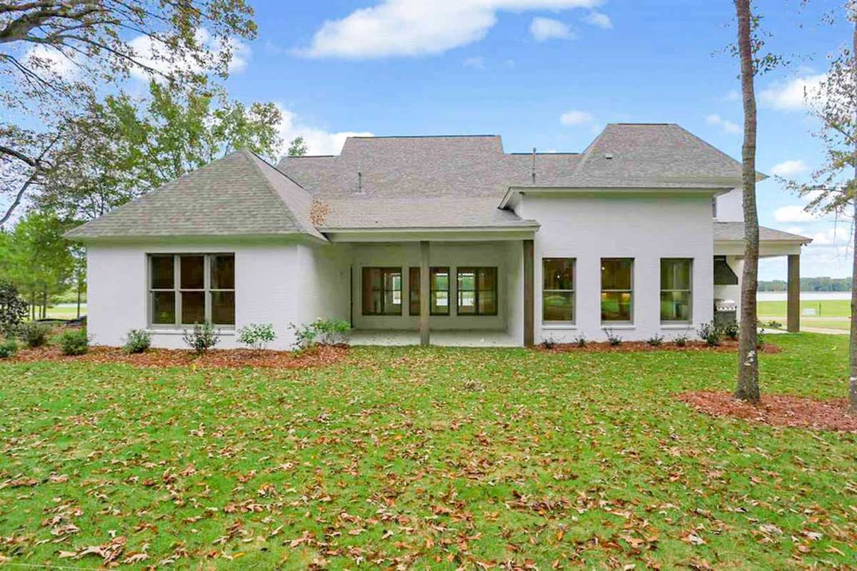 House plan exterior: single-story with hip roof, large covered patio, and multiple gable dormers.