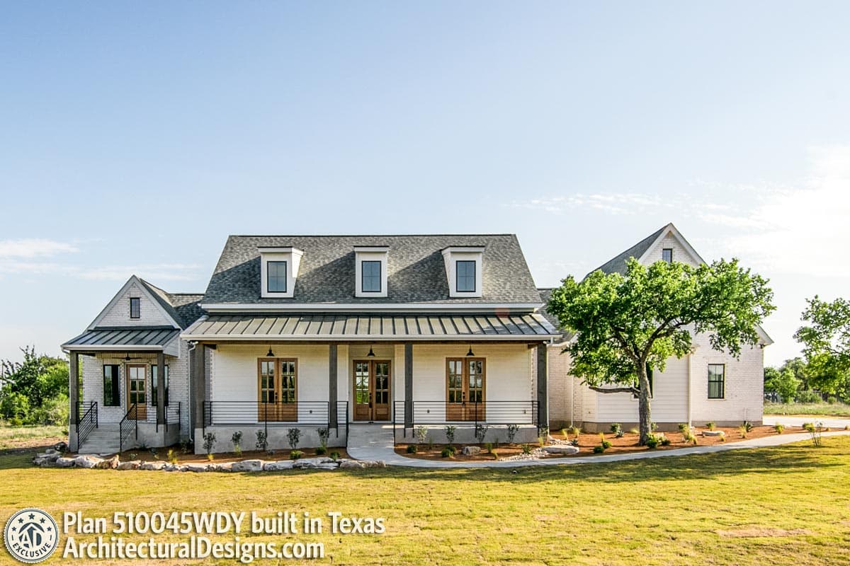 Modern Farmhouse house plan exterior with a covered porch, metal roof, dormers, and white brick accents.