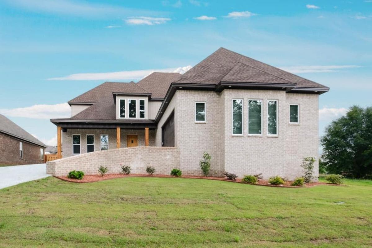 House plan exterior. Two-story home with Craftsman style elements. Features include gabled roof, brick facade, and covered porch with wooden supports.