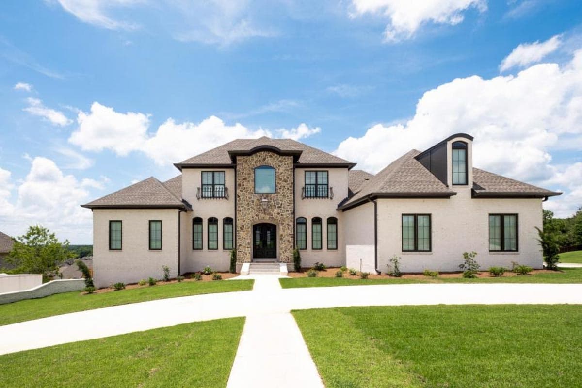 House plan exterior: Two-story residence with stone-accented entryway, multiple gables, and arched dormer.
