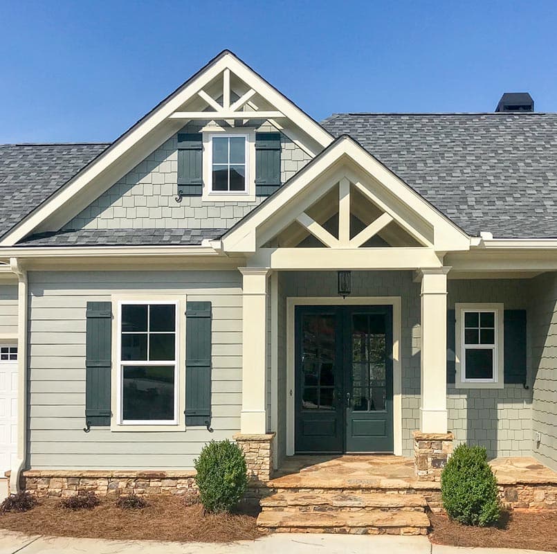 Modern farmhouse house plan exterior with gabled entrance, double doors, decorative gables, and shake siding.