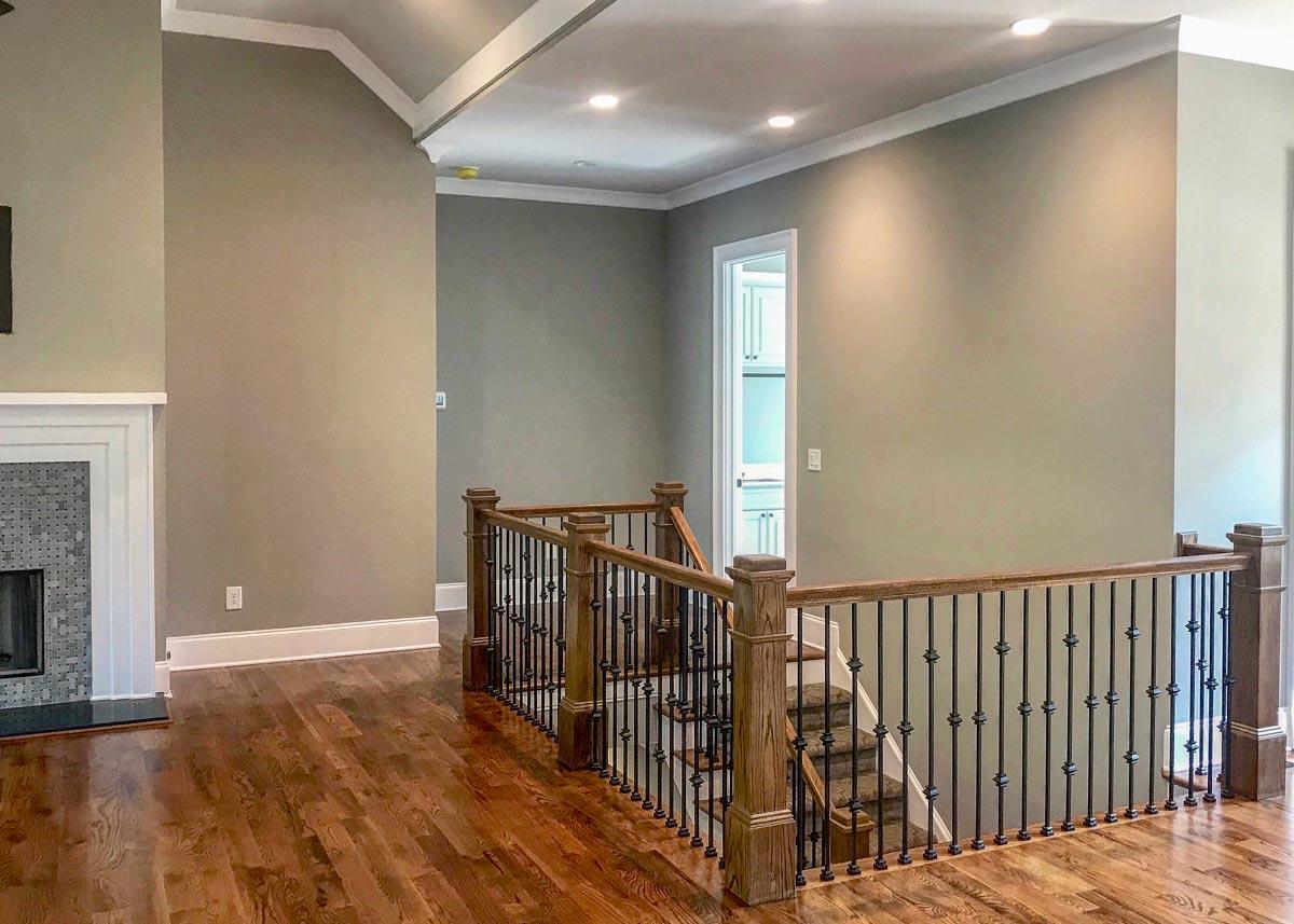 Interior view showing a staircase with wood railings and metal spindles, leading to a hallway with a doorway.