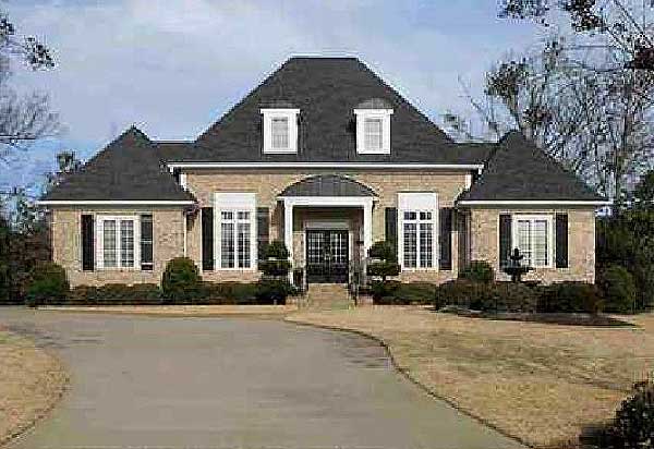 House plan exterior: Brick facade, two stories, symmetrical gables, arched portico, dormers, and bay windows.