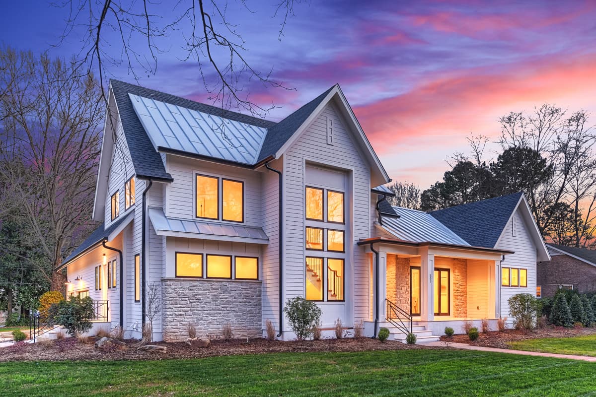 House plan exterior: Modern style, two stories, white siding, metal roof, stone accents, large windows, and covered front porch.