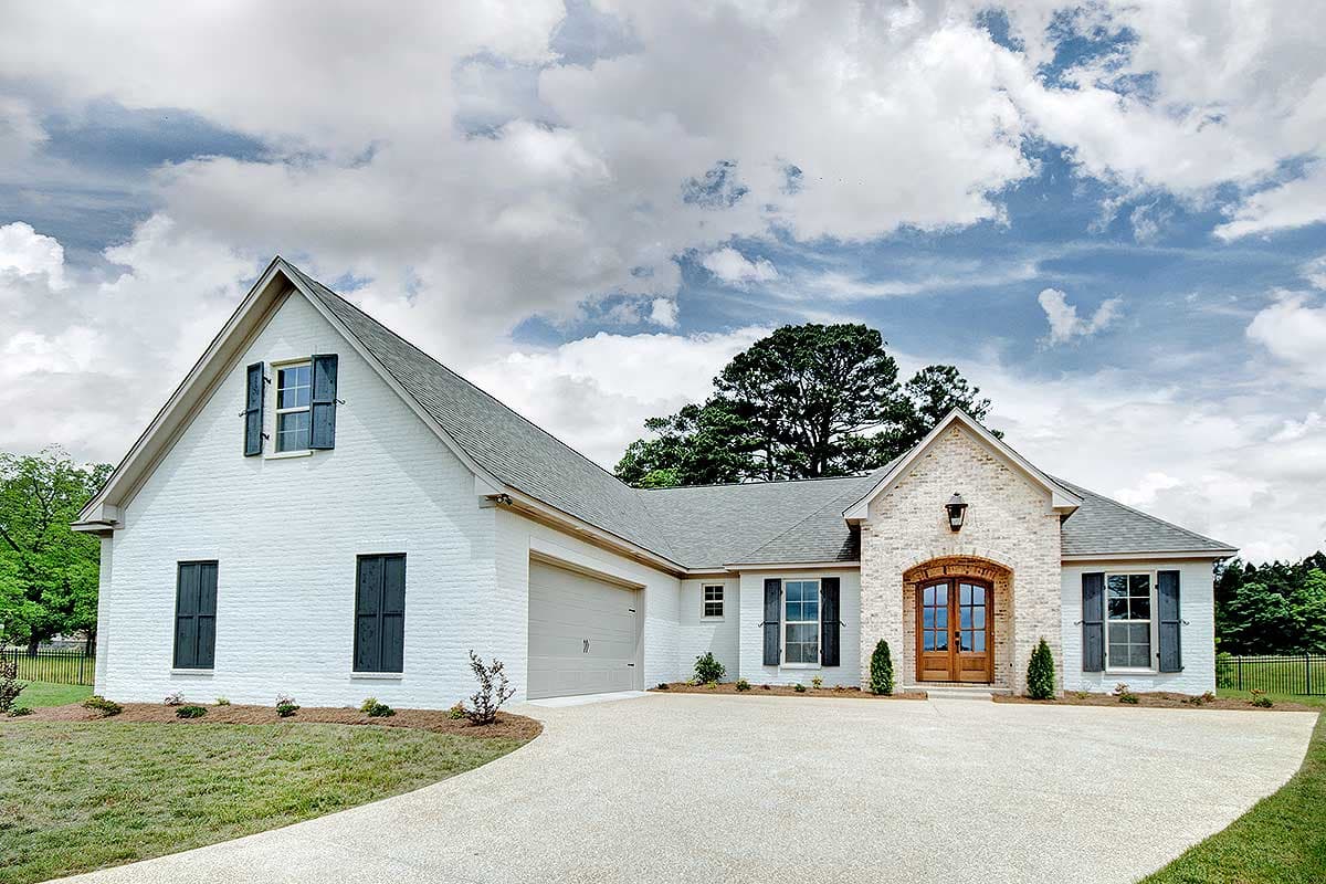 House plan exterior with brick accents, gable roof, and a two-car garage. Features include wood door, shuttered windows, and a driveway.