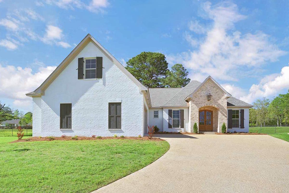 House plan exterior of a white brick two-story home with a prominent gabled dormer, brick entry arch, and double front doors.