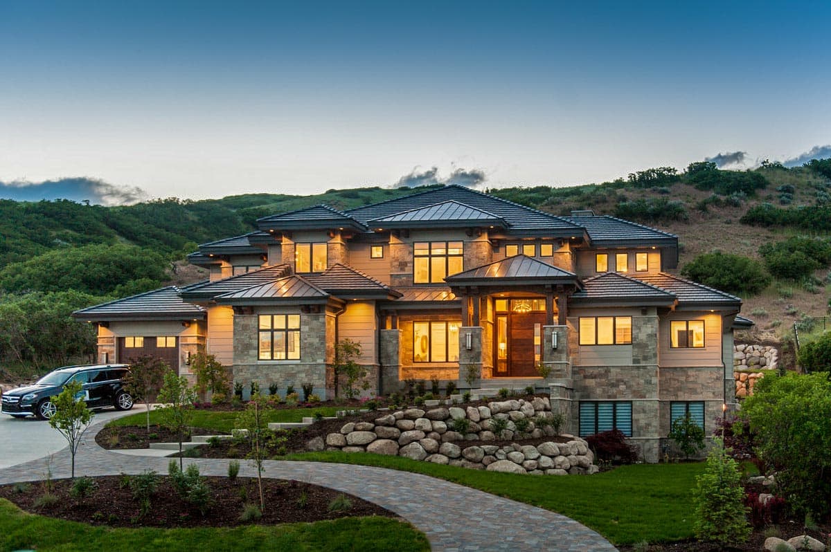 House plan exterior with modern lines, layered rooflines, stone and wood facade, and a prominent covered entry.