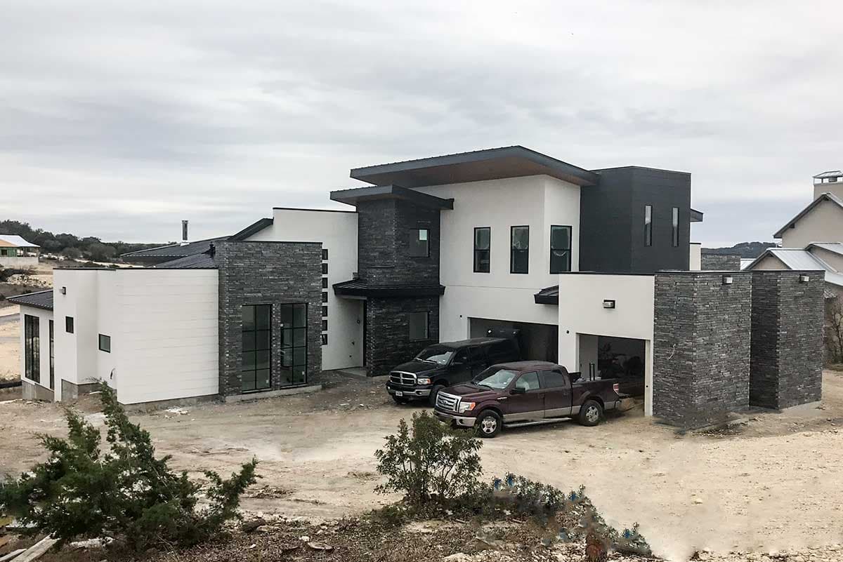 Modern house plan exterior with stacked stone accents, flat rooflines, and a three-car garage.