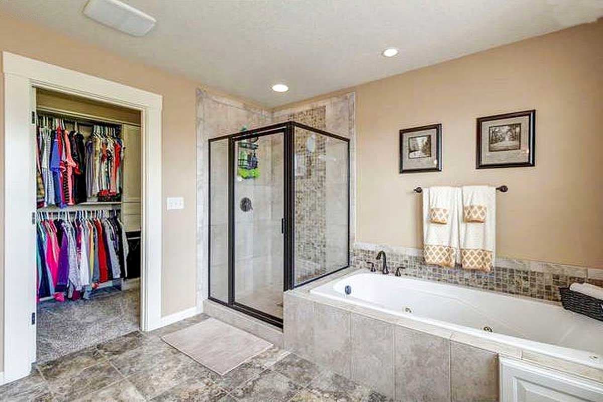 Master bathroom with soaking tub, glass-enclosed shower, and walk-in closet.