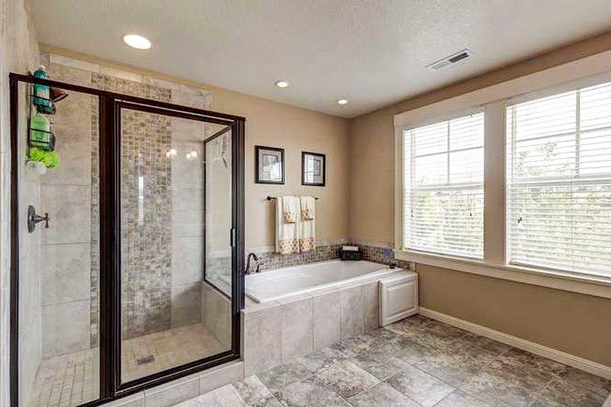 Bathroom with glass-enclosed shower, soaking tub, tiled walls, and large windows.