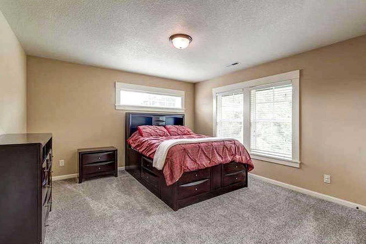 Bedroom with a bed featuring built-in drawers, two windows, and carpet.