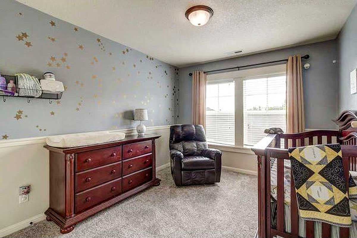 Nursery with crib, dresser, recliner, and window.
