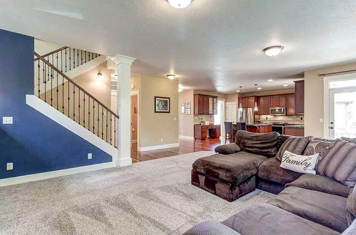 Interior view of open-concept living area with dark wood cabinetry, kitchen island, and staircase with metal balusters.