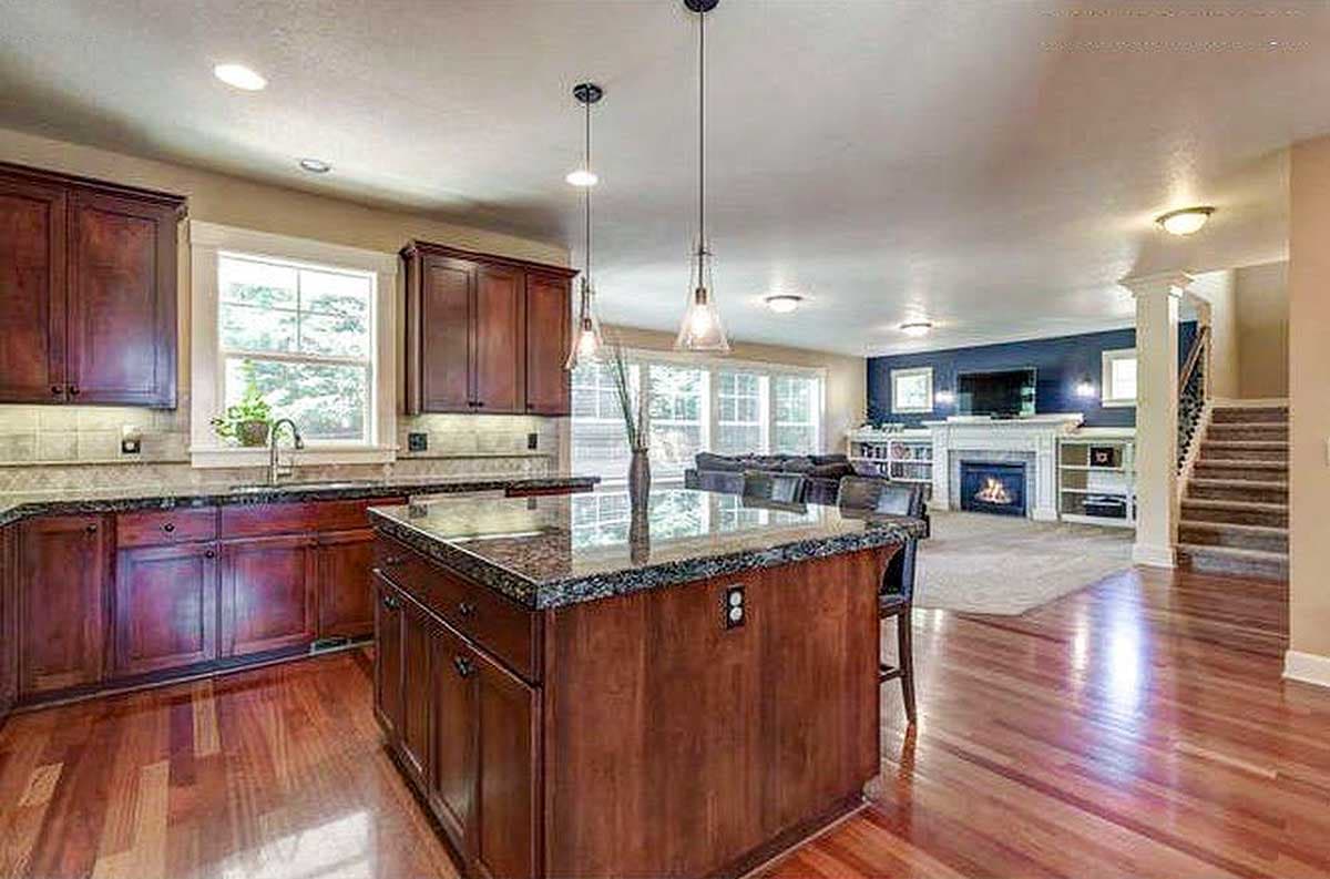 Open-concept interior view showing a kitchen with a center island and a living area with a fireplace.