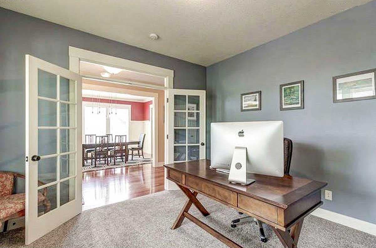 Home office with double glass doors opening to dining room with large table and chairs.