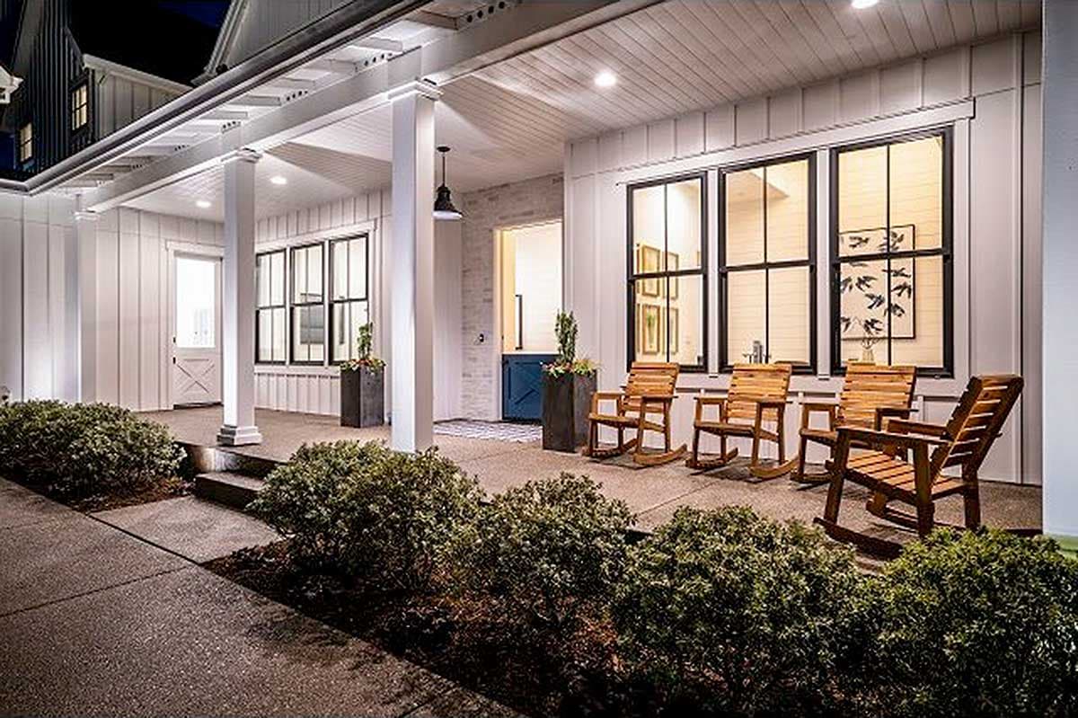 House plan exterior with covered porch, white board-and-batten siding, multiple gables, and large grid windows.