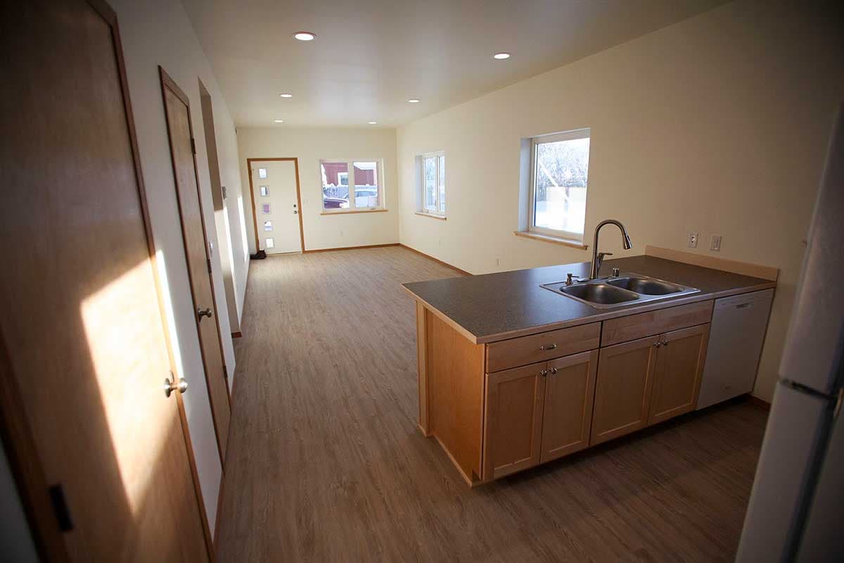 Interior view of a house plan showing a kitchen area with a double sink island and adjacent living space with doors and windows.