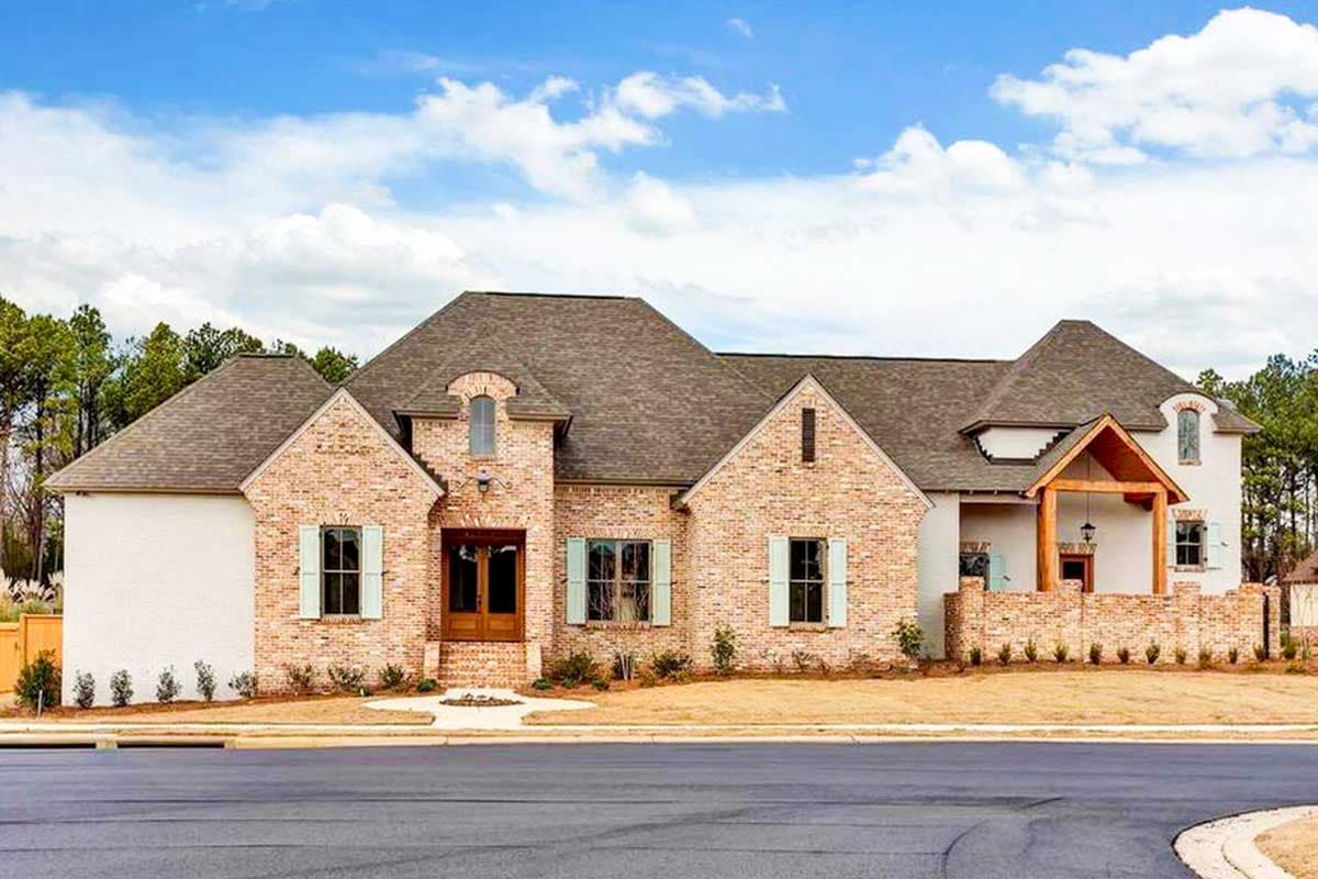 House plan exterior with brick and stucco facade, gabled roof, and arched window above the front door. Features a covered porch.