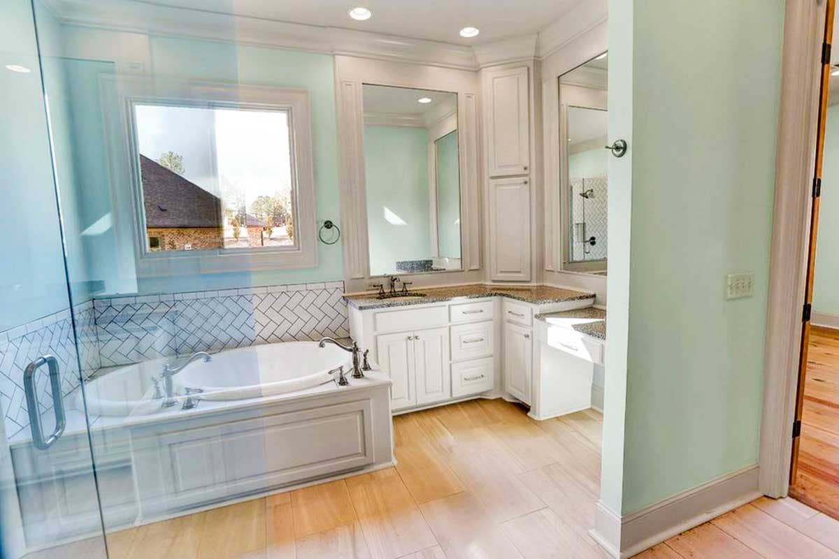 Master bathroom with soaking tub, dual vanity with granite countertops, and a glass-enclosed shower.