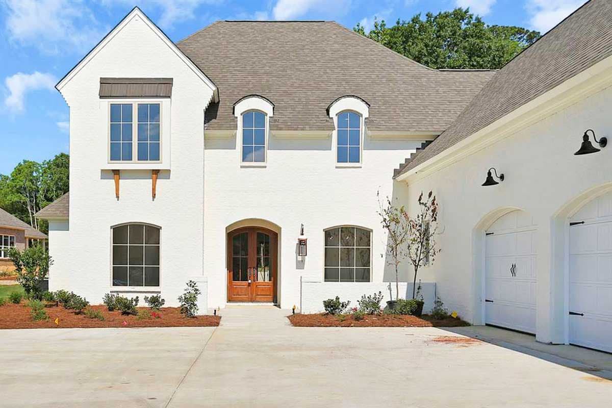 House plan exterior: Two-story white brick home with arched double doors, arched windows, gable, and attached two-car garage.