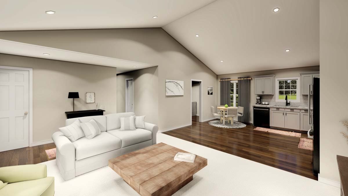 Open-concept living space with vaulted ceiling, featuring a sofa, dining area, and kitchen with gray cabinetry and a window.