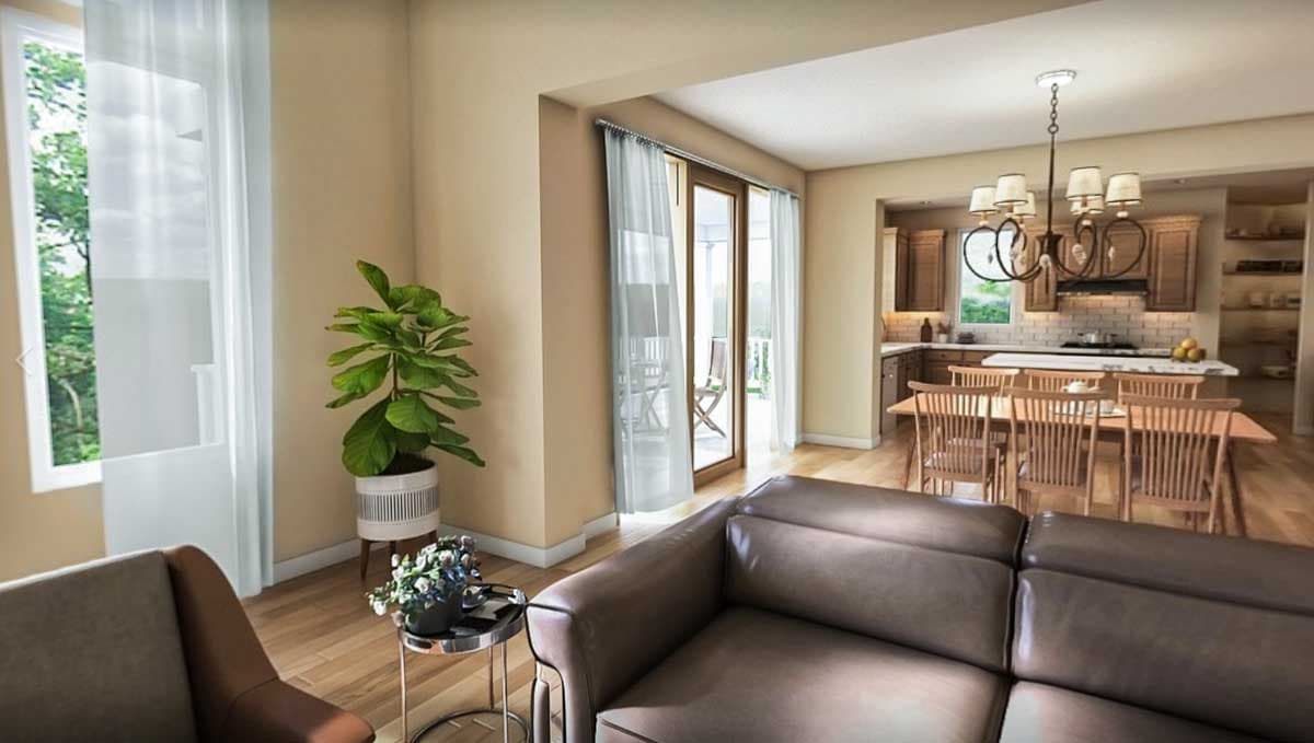 Interior view of an open-concept living area with a sectional sofa, dining table, and kitchen with wood cabinets.