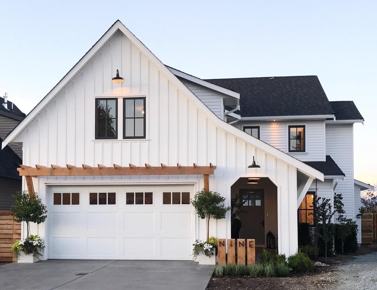 Modern Farmhouse exterior with white board and batten siding, gabled roof, carriage garage door, and covered entry.