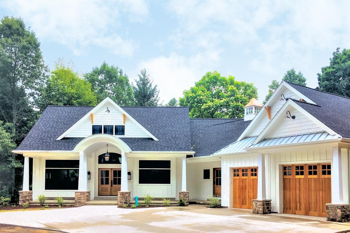House plan exterior with Craftsman style, one story, and a front porch with gables and a two-car garage with wood doors.