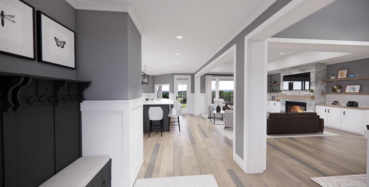 Interior view showing entryway, kitchen island with bar stools, and living room with stone fireplace and built-in shelving.